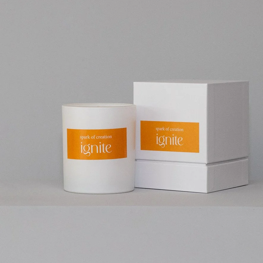 A white mug, a white box, and orange printed materials are arranged on a light gray surface against a gray background.
