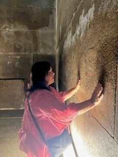 A person touching a sandy or textured wall in a dark environment.