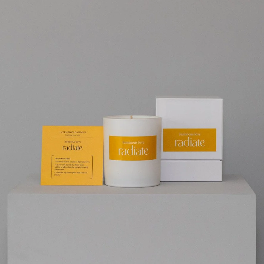 A white container with a yellow label and white box packaging are displayed on a grey surface against a grey background.