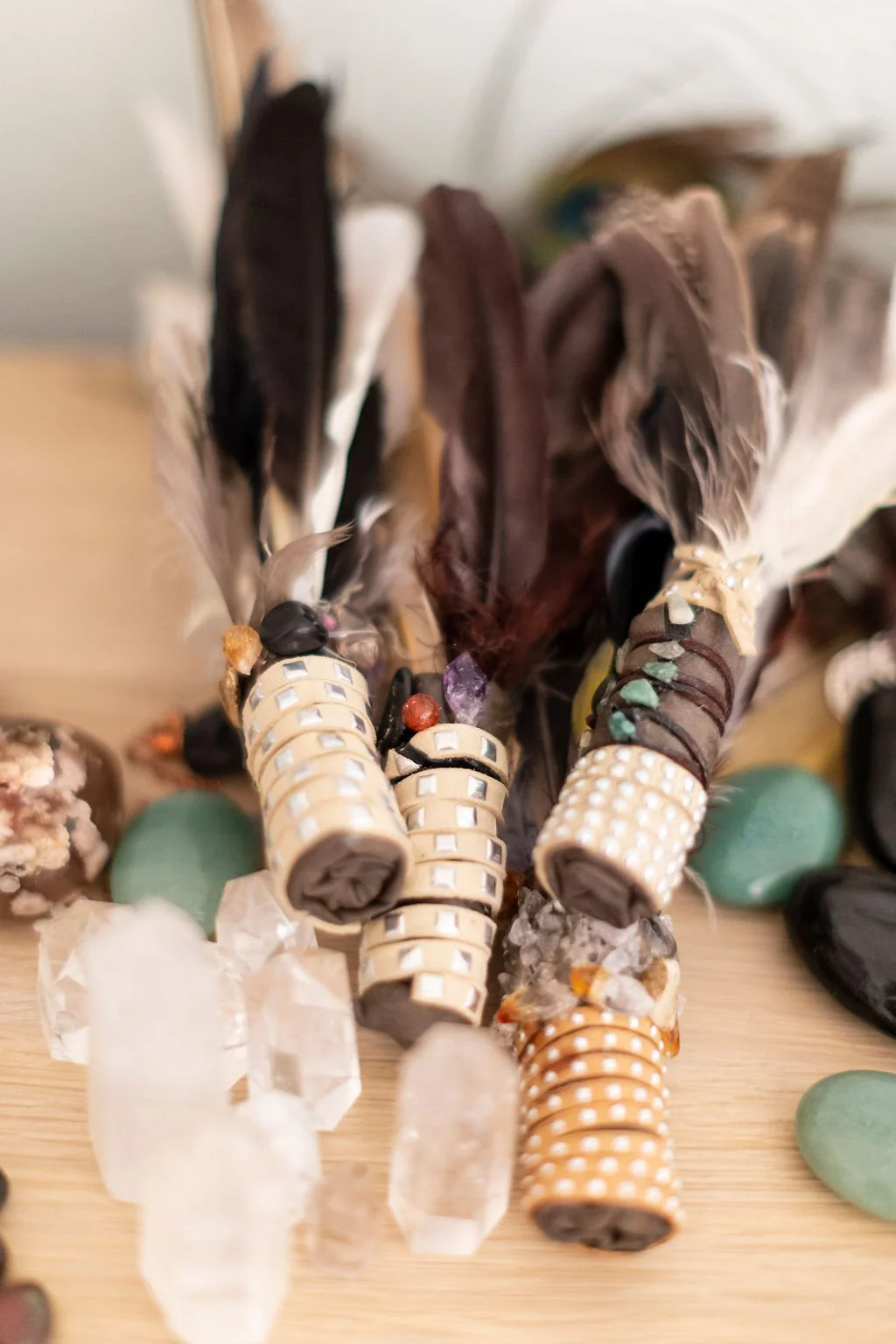 A collection of decorative feathers and jewelry, including beaded bracelets and stones, arranged on a wooden surface.