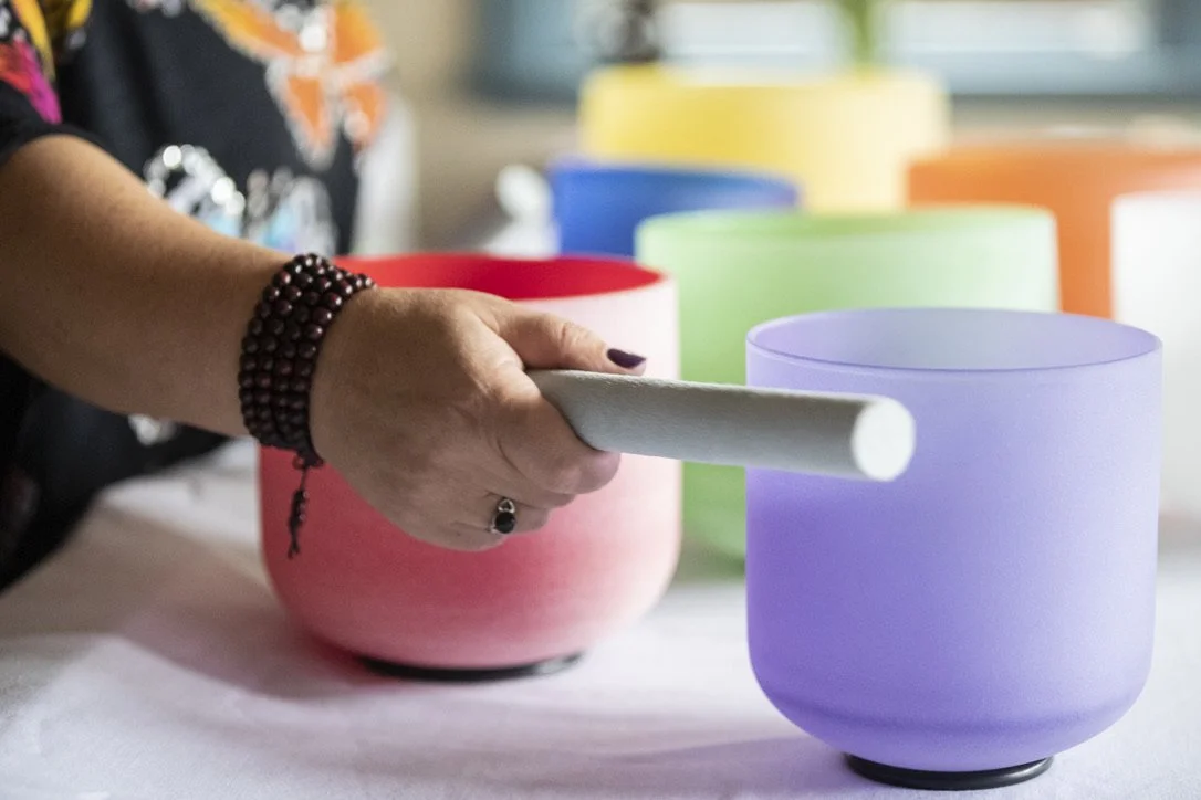 Maria Davis playing crystal singing bowls in shades of red, green, and purple