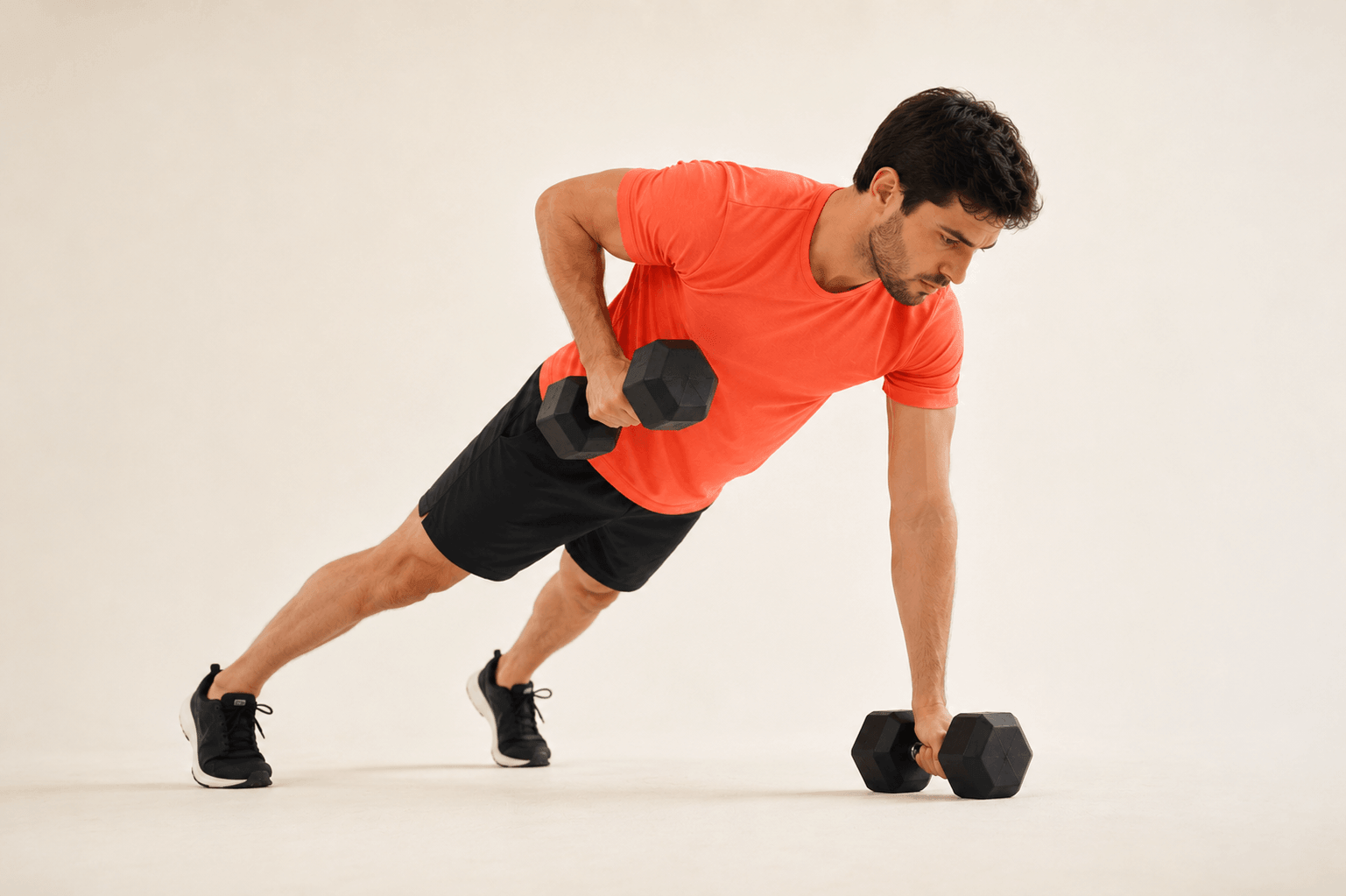 Mann macht eine Seitstütz-Übung mit Kurzhanteln in einem Fitnessraum.