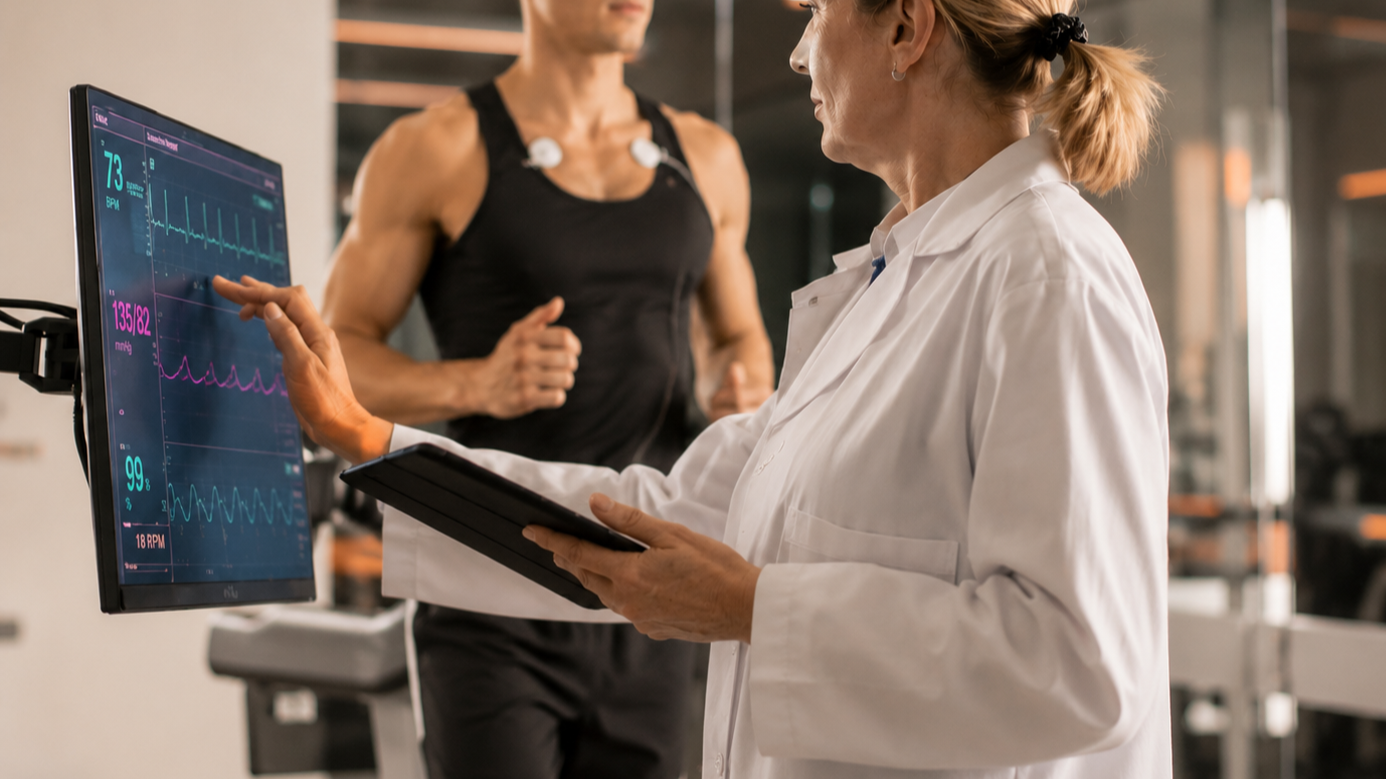 Therapeutin überprüft Herzfrequenz und Vitalwerte eines Sportlers bei einem Leistungsdiagnostik-Test.