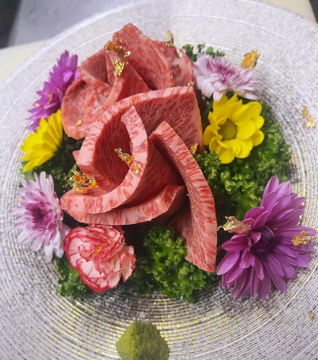 金箔が飾られた花の盛り合わせと薄切りの霜降り和牛の刺身