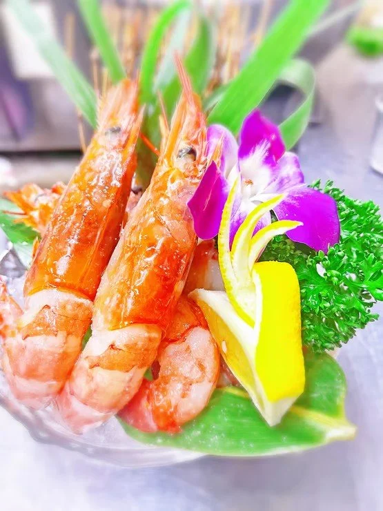 エビの刺身盛り合わせと花とレモンの飾り付け