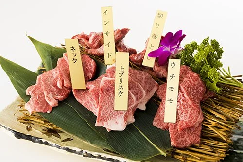 高級和牛肉の切り分けと盛り付け、各部位にタグと花が添えられている。