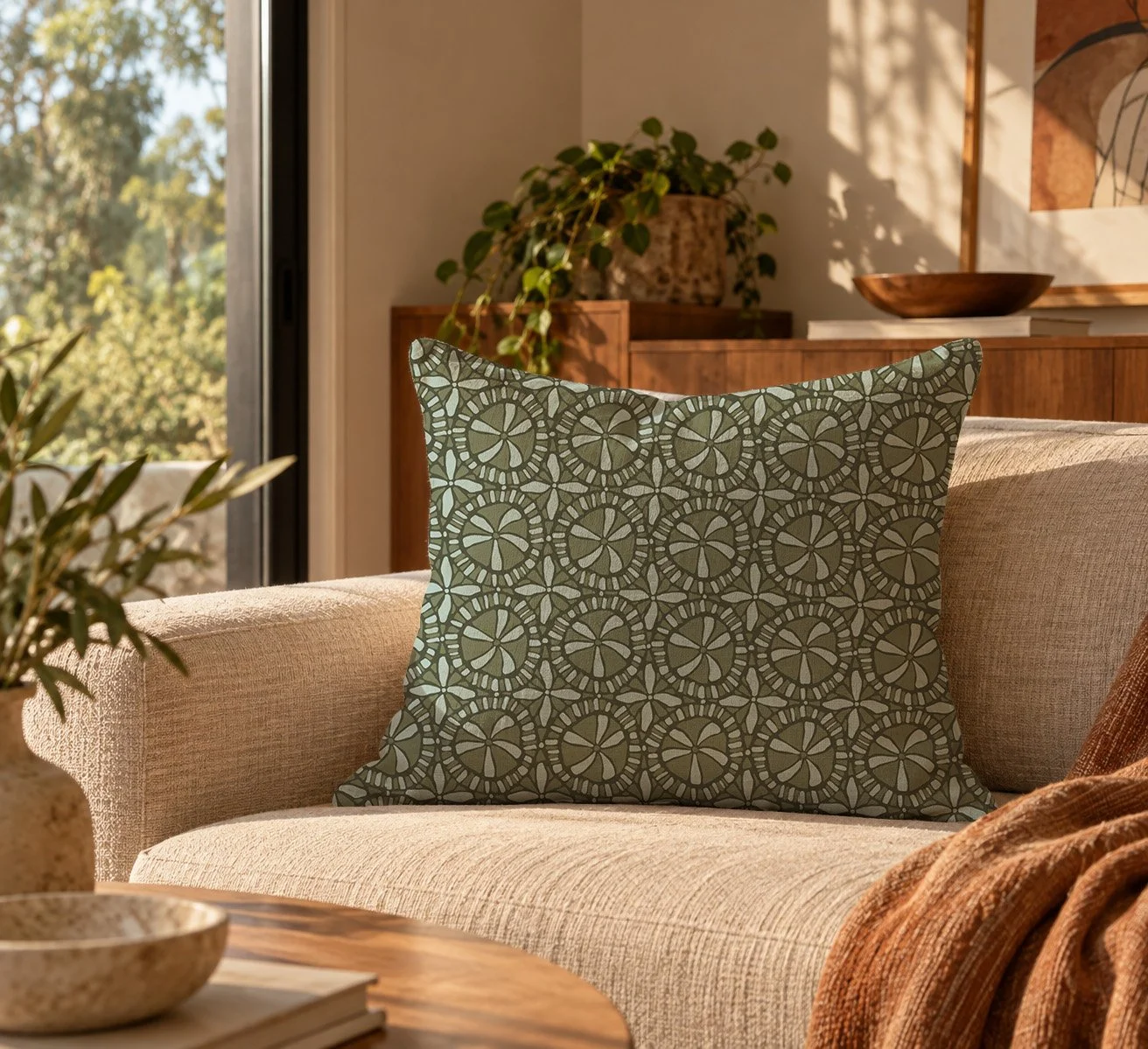 Decorative living room with patterned cushion on a beige sofa, wooden furniture, potted plants, and sunlight through open window.