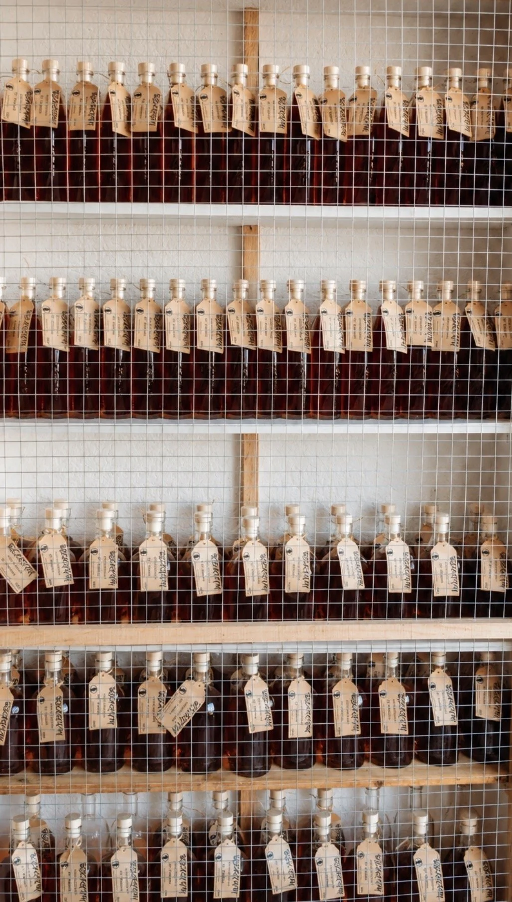 Liqueurs dans des bouteilles alignées sur des étagères derrière une grille en fil métallique.