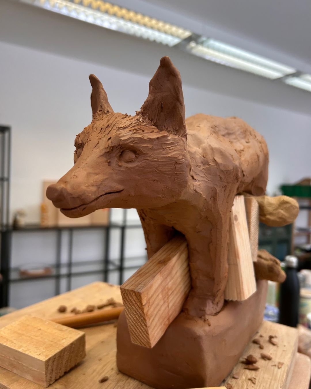 Holzskulptur eines Hundes, die auf einer Werkbank im Künstleratelier steht.