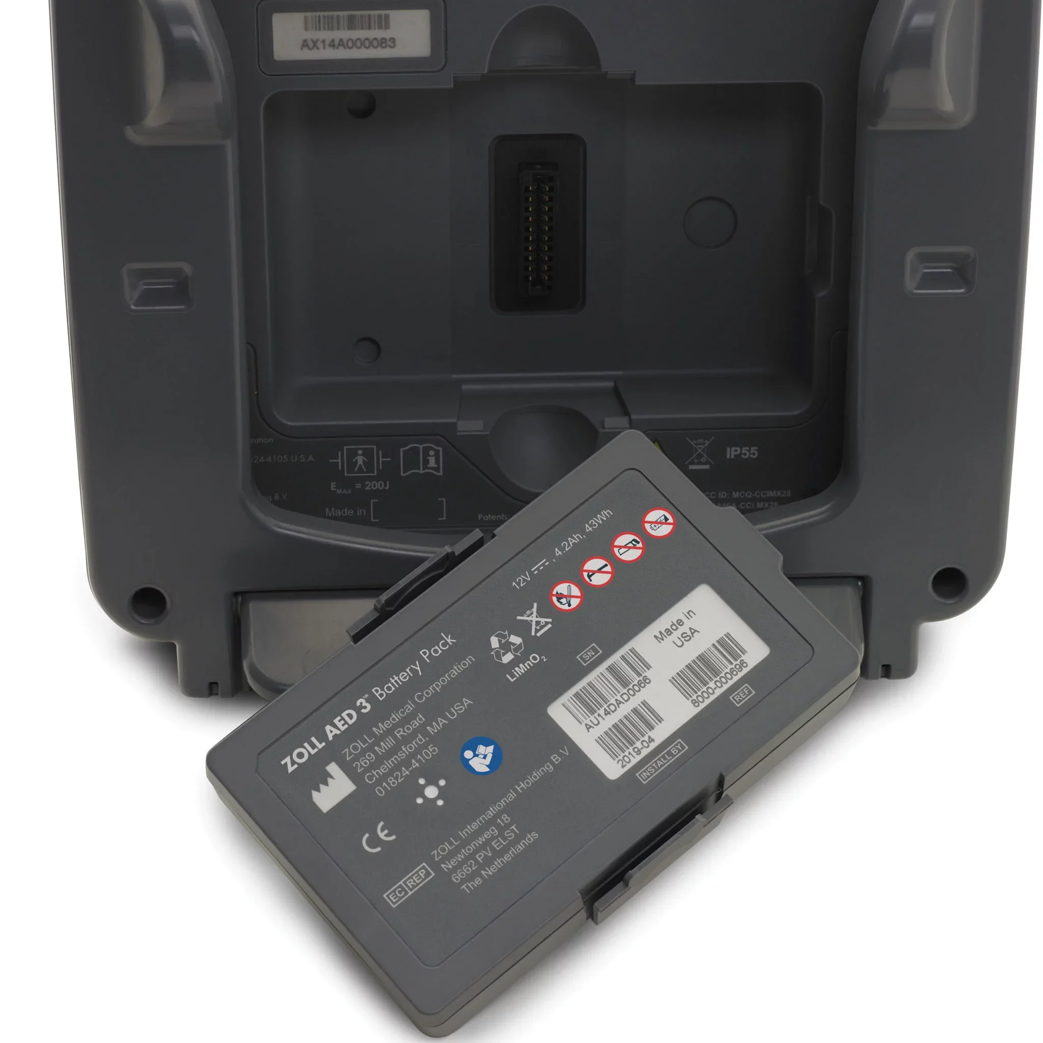 Vue de face d'un boîtier gris de dispositif médical avec un compartiment ouvert contenant une batterie rechargeable et un étiquetage contenant des informations techniques et de conformité.
