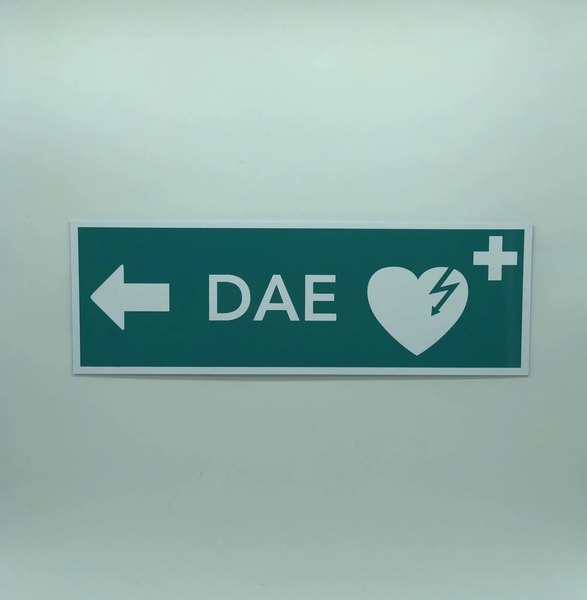 Un panneau indiquant la direction d'urgence vers la zone de premiers secours, avec une flèche blanche pointant vers la gauche, une croix blanche et le mot 'PAST' en grandes lettres.