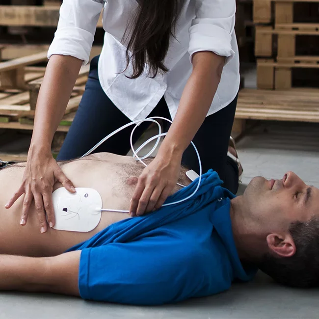 Une personne effectue une réanimation cardio-respiratoire sur un homme allongé, utilisant un défibrillateur.
