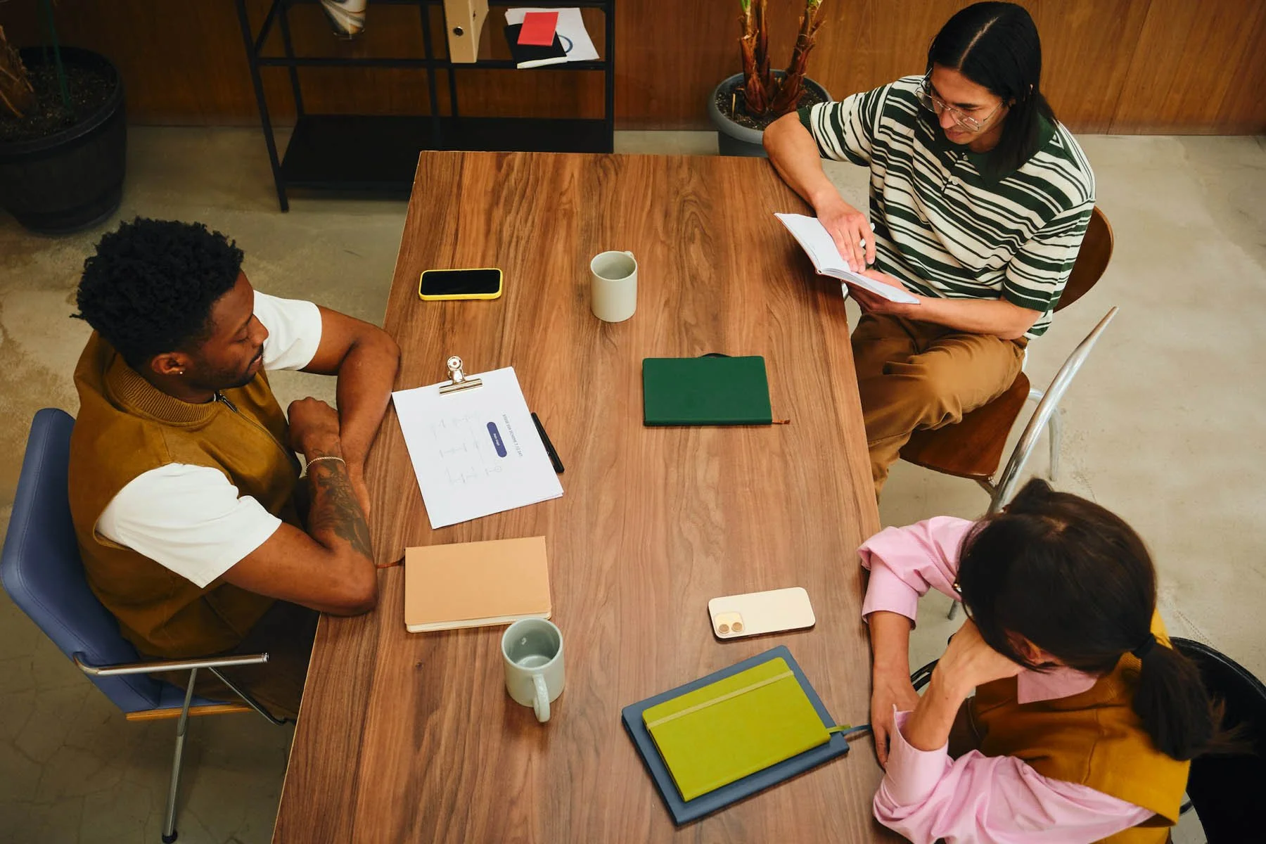 Four people sitting around a wooden table in a casual meeting or discussion.