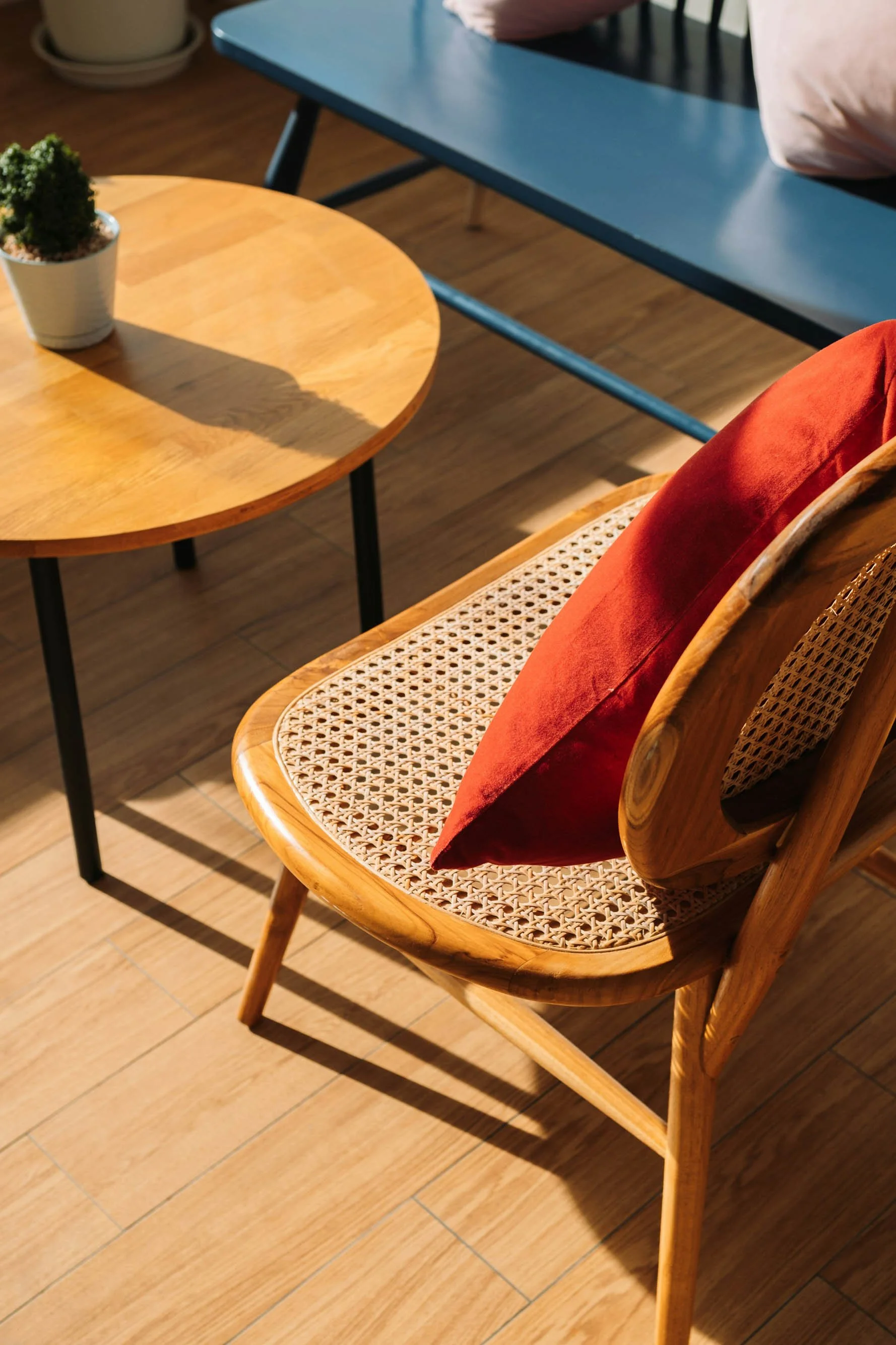 Wooden chair with a red cushion and woven cane seat.