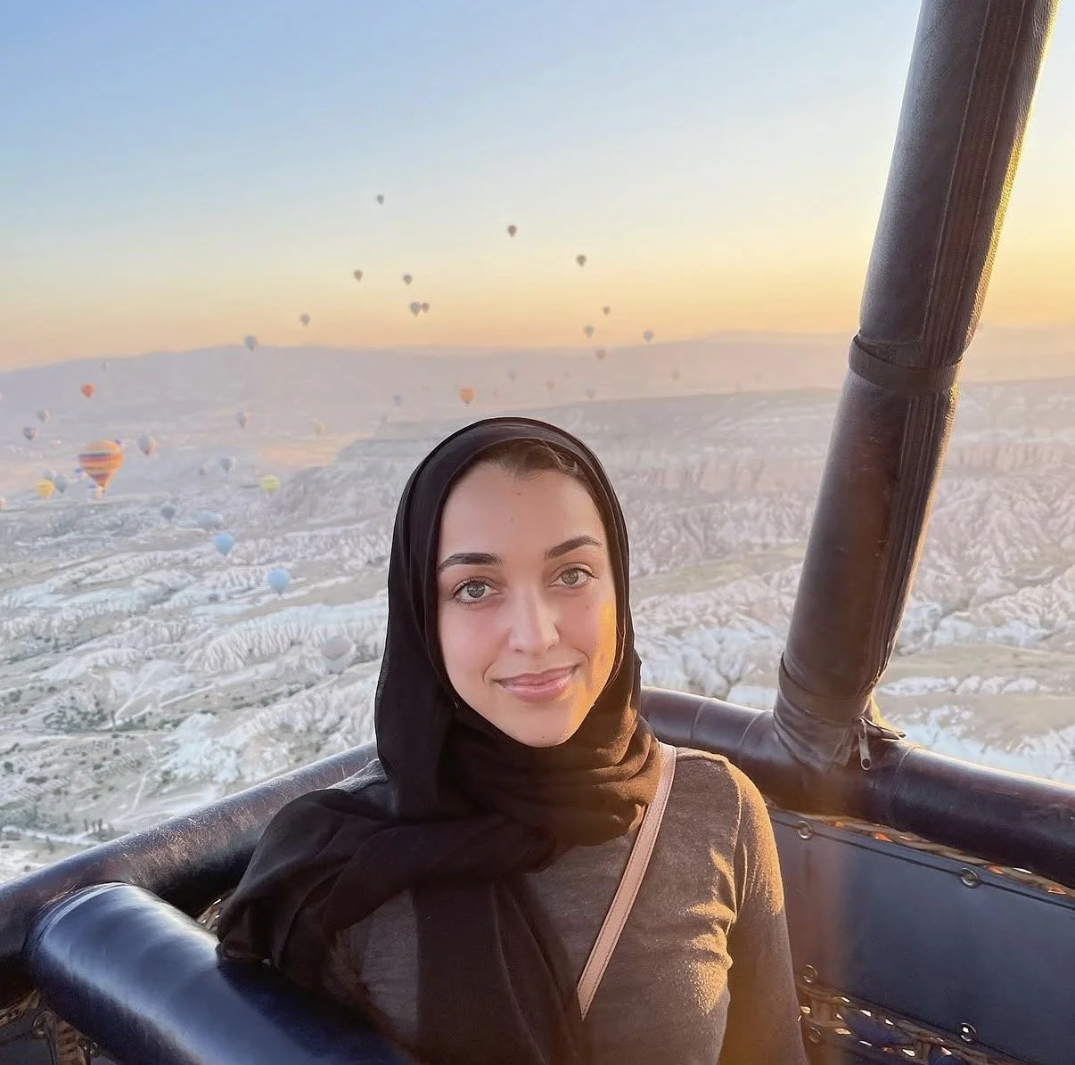 Woman in a hot air balloon over a rocky valley at sunset