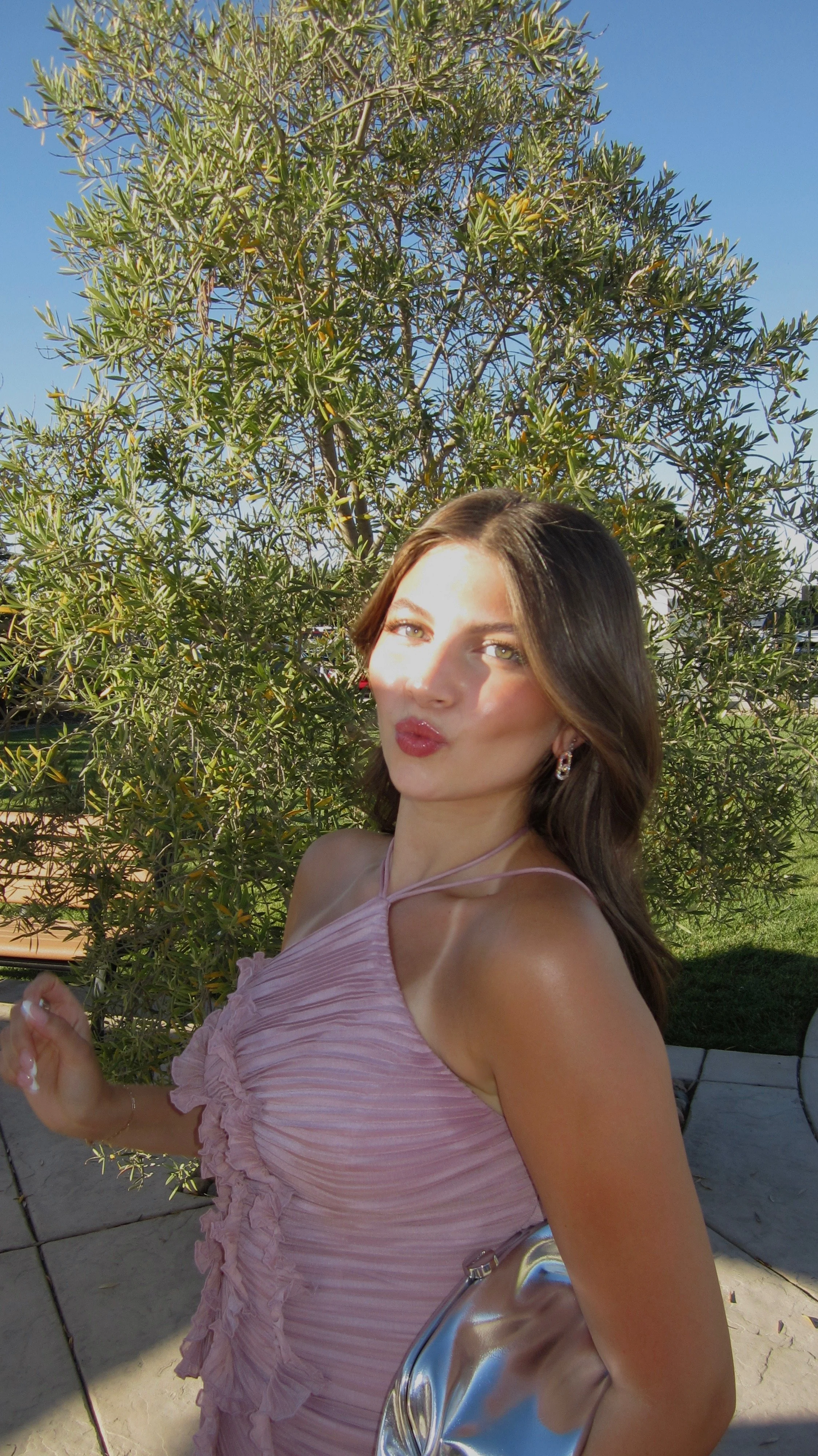 Woman in a pink dress taking a selfie outdoors