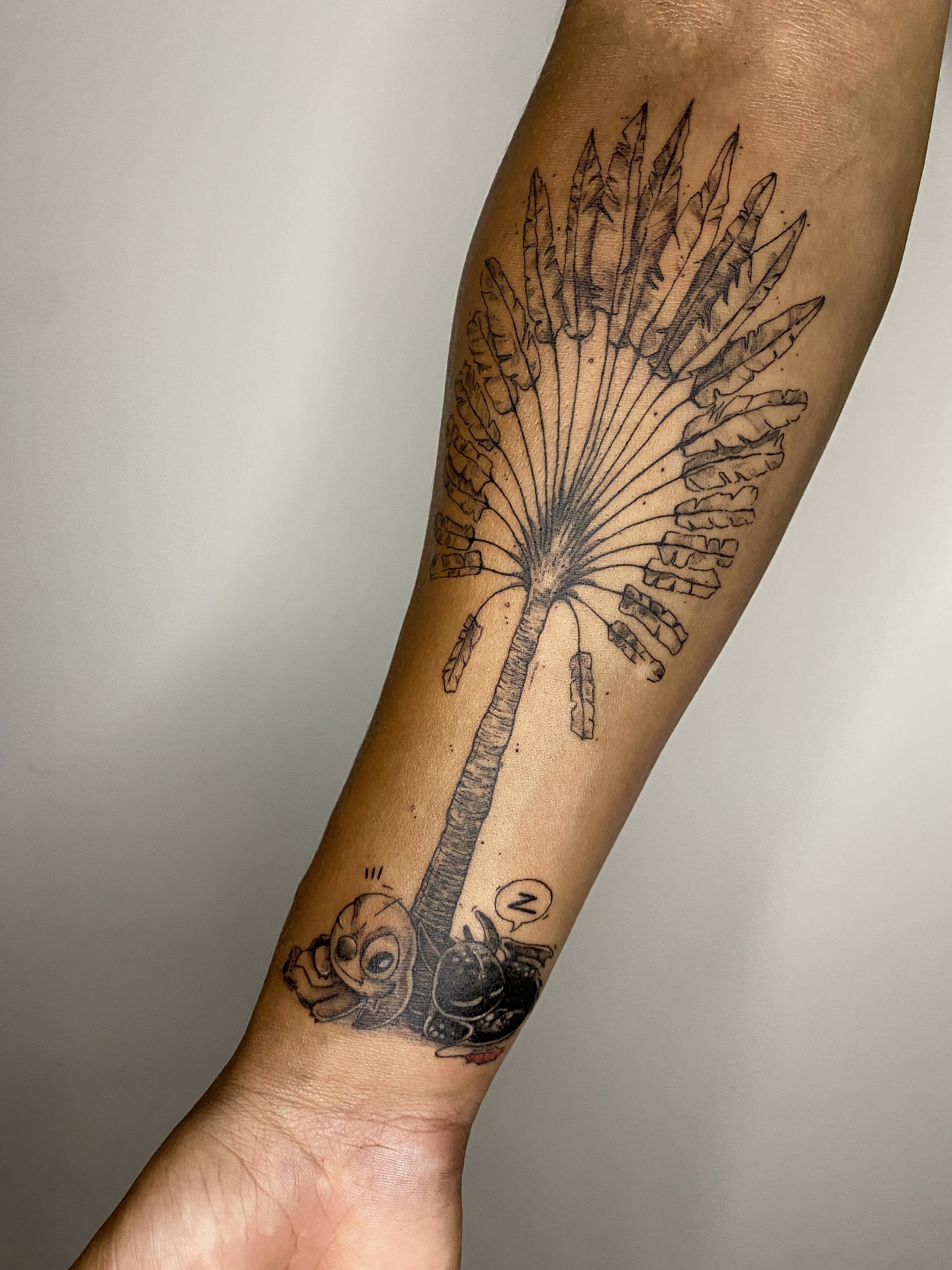 Tatouage d'une plume d'oiseau sur le bras d'une personne, avec un dessin d'une abeille en bas.