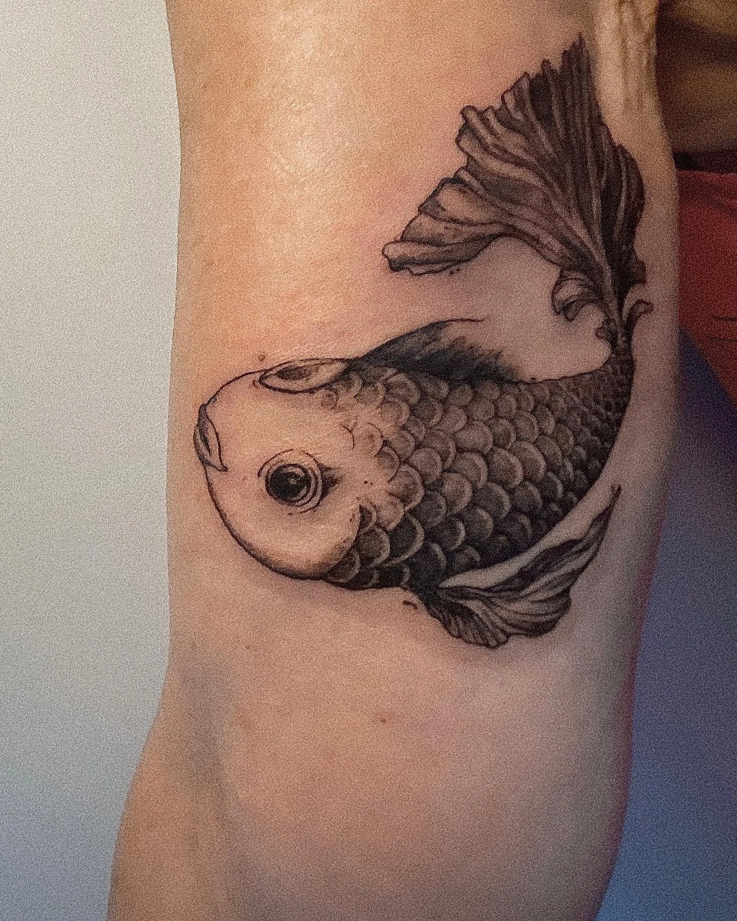 Tatouage noir d'un poisson nageant sur la peau humaine.