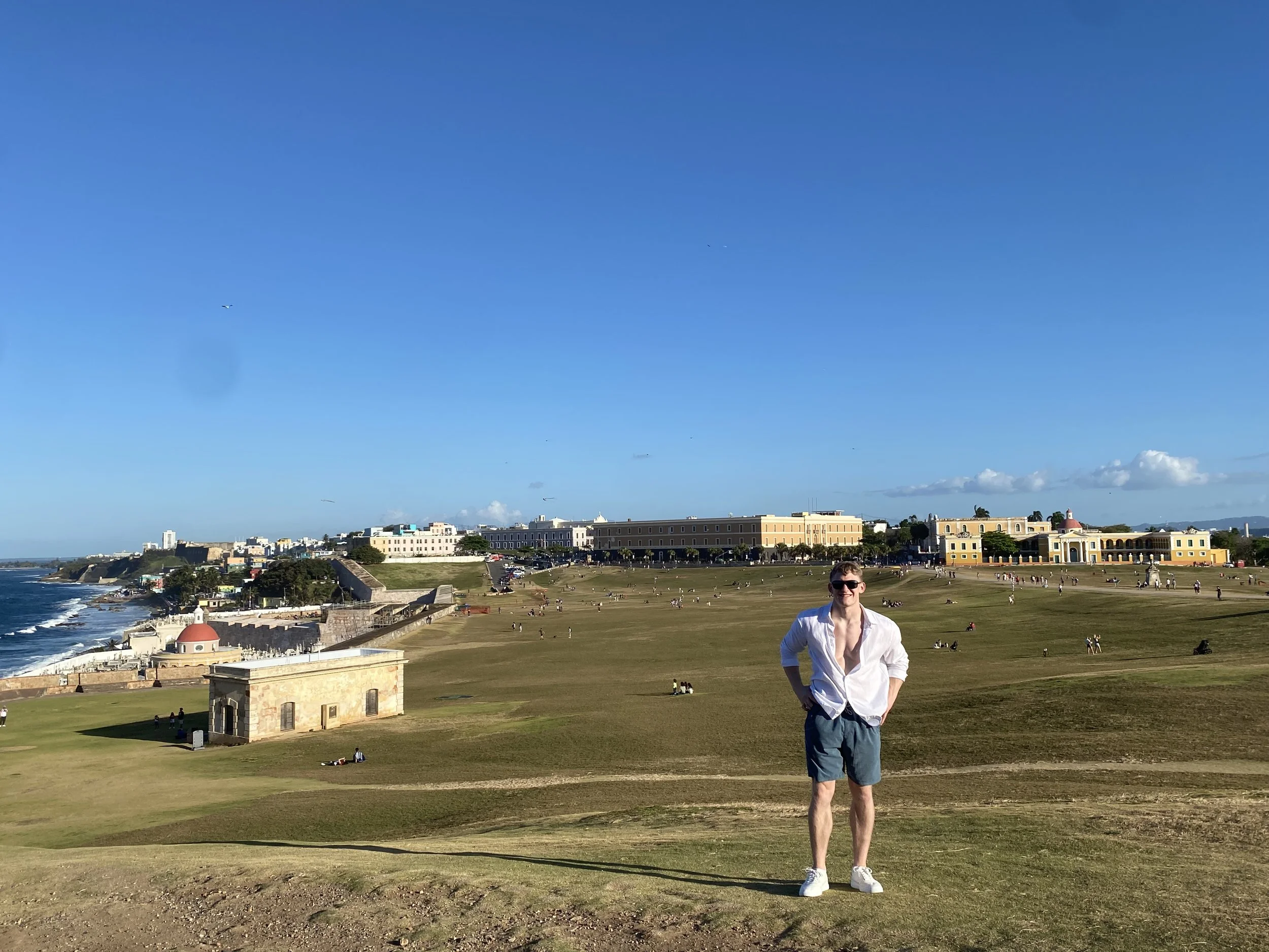 The young and smiling writer in a white shirt and shorts standing in the beautiful landscape of Puerto Rico.