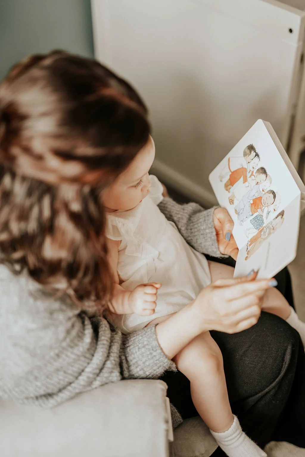 Renee, a baby and toddler sleep consultant, reading a children's picture book to her daughter sitting on her lap.