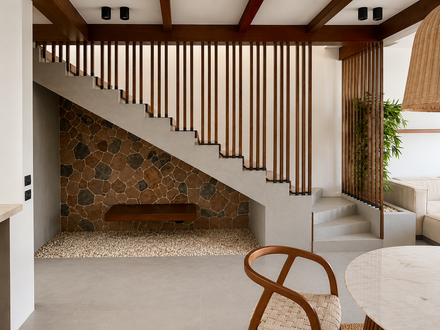 Modern interior space with a staircase featuring a stone wall, wooden slats, and concrete steps, with a cozy seating area and a green plant.