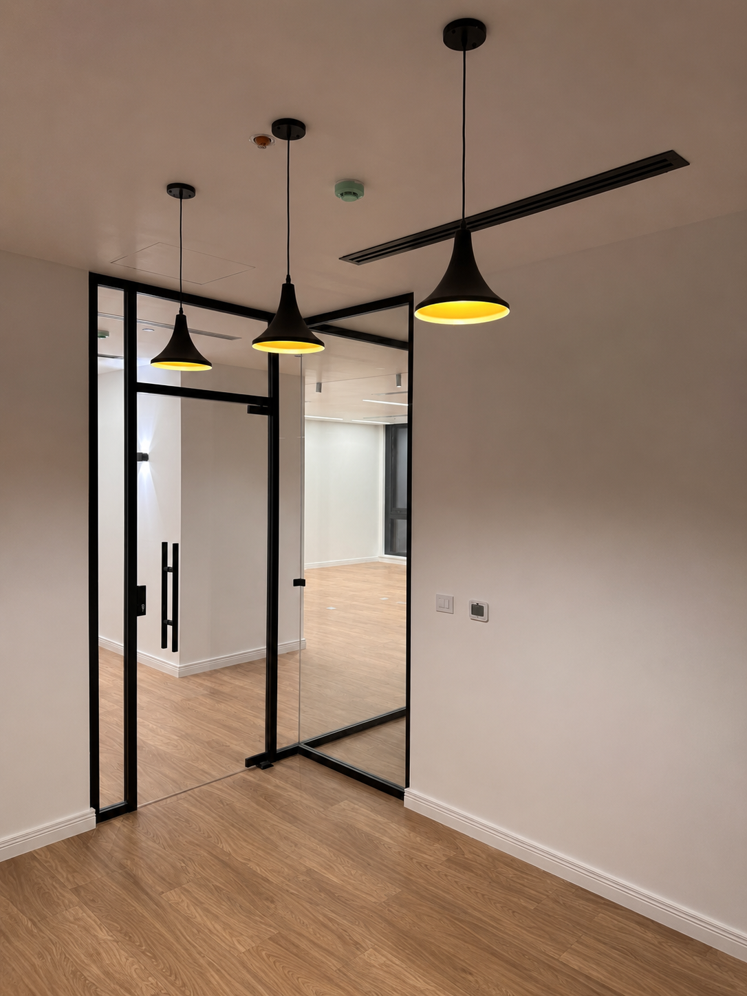 Modern interior with black pendant lights, glass sliding doors, and wooden flooring.