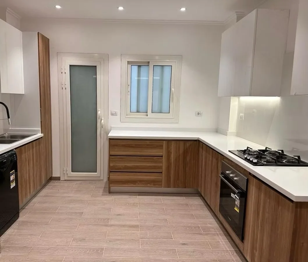 Modern kitchen with wood and white cabinetry, a window, a glass door, a gas stove, an oven, and a sink.