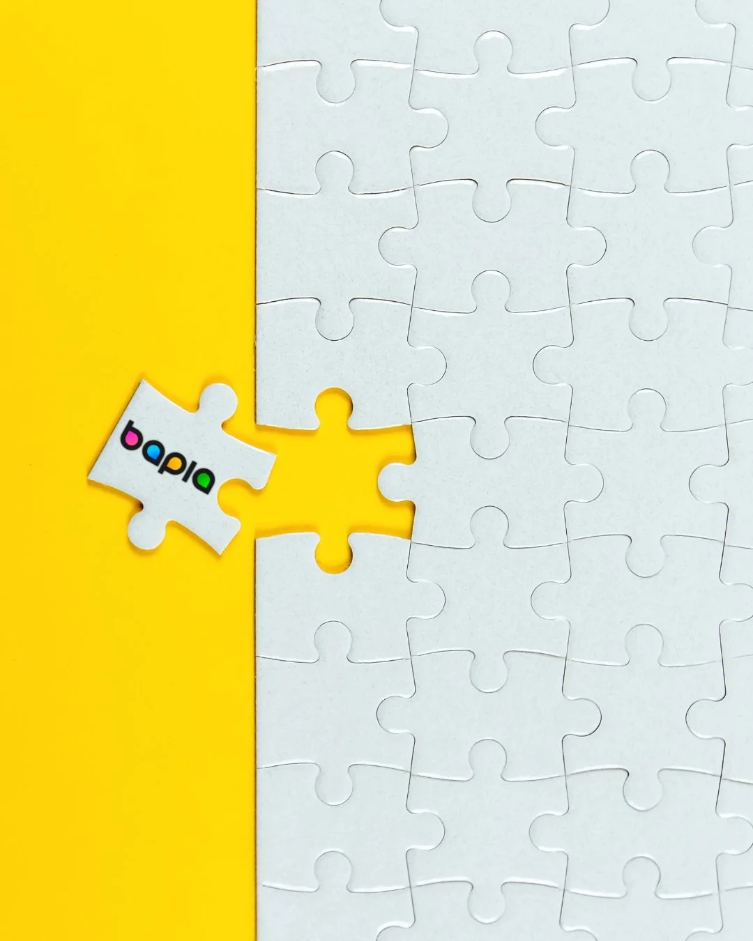 A partially completed white jigsaw puzzle on a yellow background with a single piece labeled 'bap.bu' beside it.