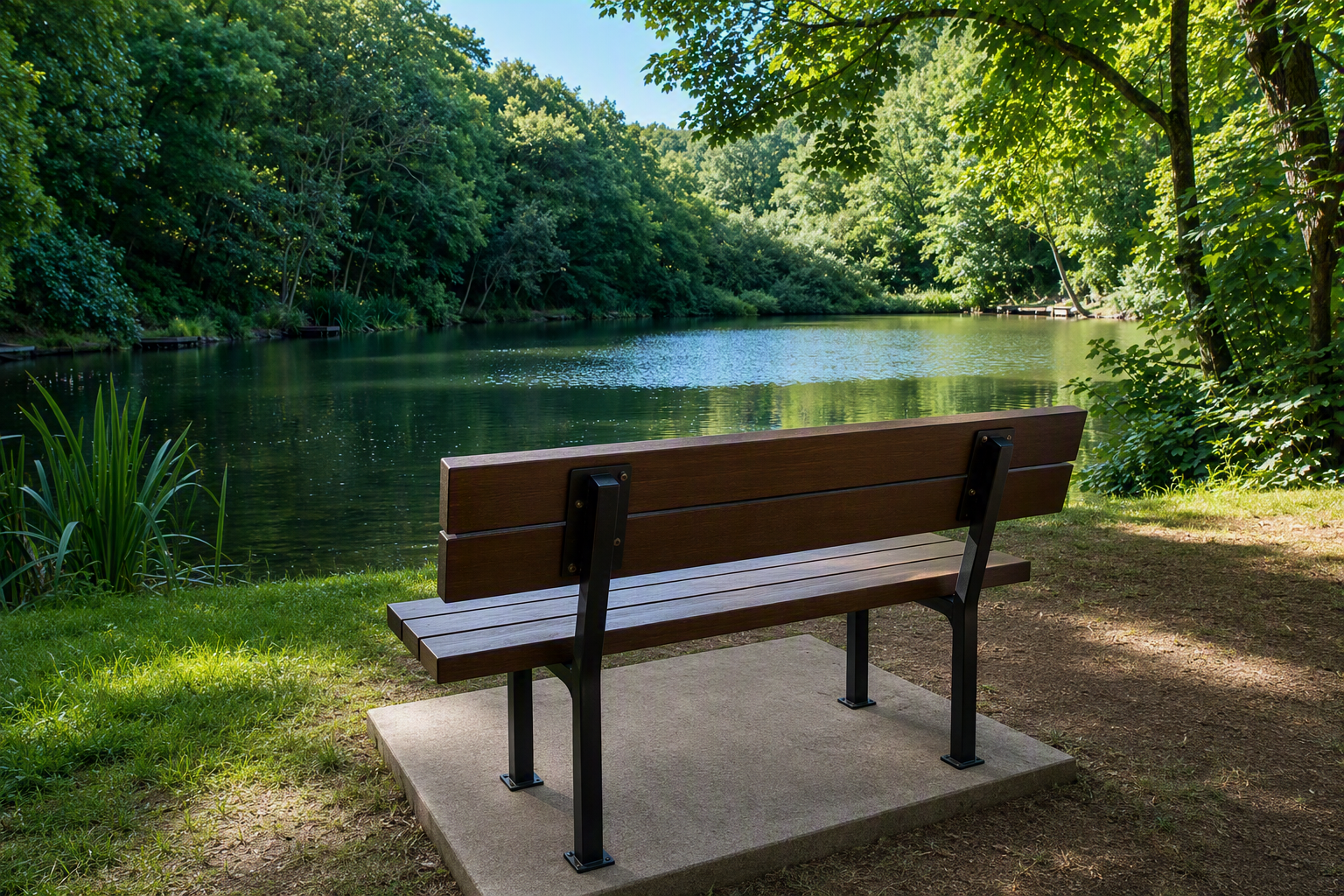 A wooden park bench facing a peaceful river with lush green trees on both sides, under a partly cloudy blue sky.