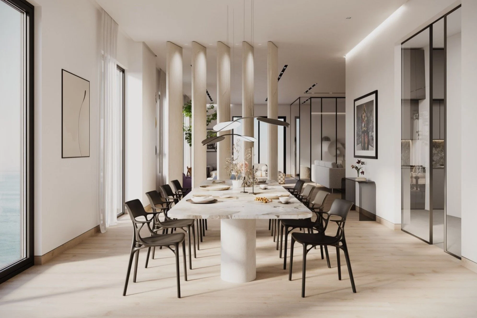 Modern dining room with a long rectangular marble table, black chairs, and a pendant light fixture. Large windows with sheer curtains, framed artwork on white walls, and open space with decorative pillars and minimalistic design.
