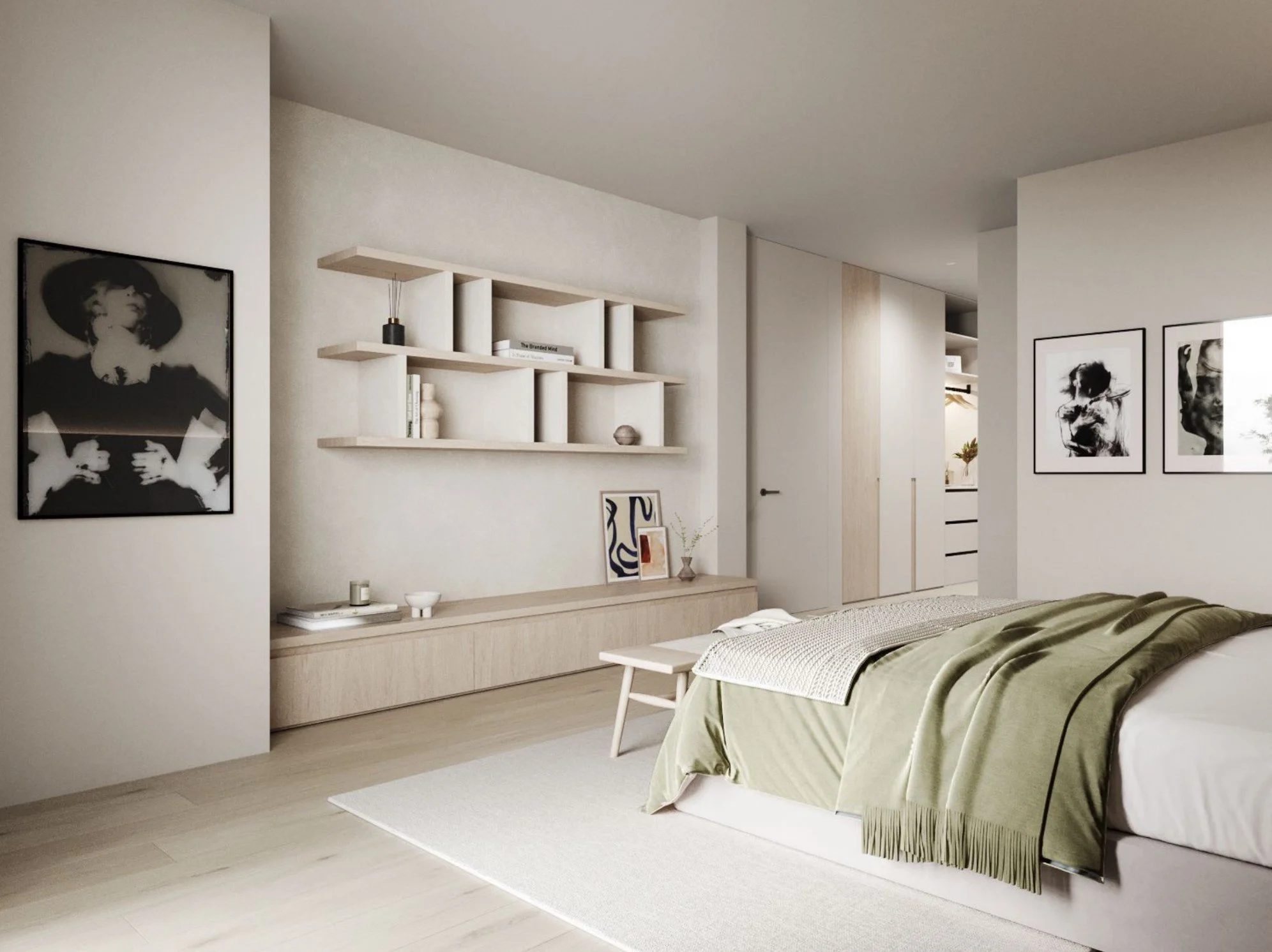 A bedroom with a bed covered in a green duvet, a wooden bench at the foot of the bed, framed black-and-white art on the walls, built-in wall shelves with decor, a beige rug, and light-colored wooden flooring.