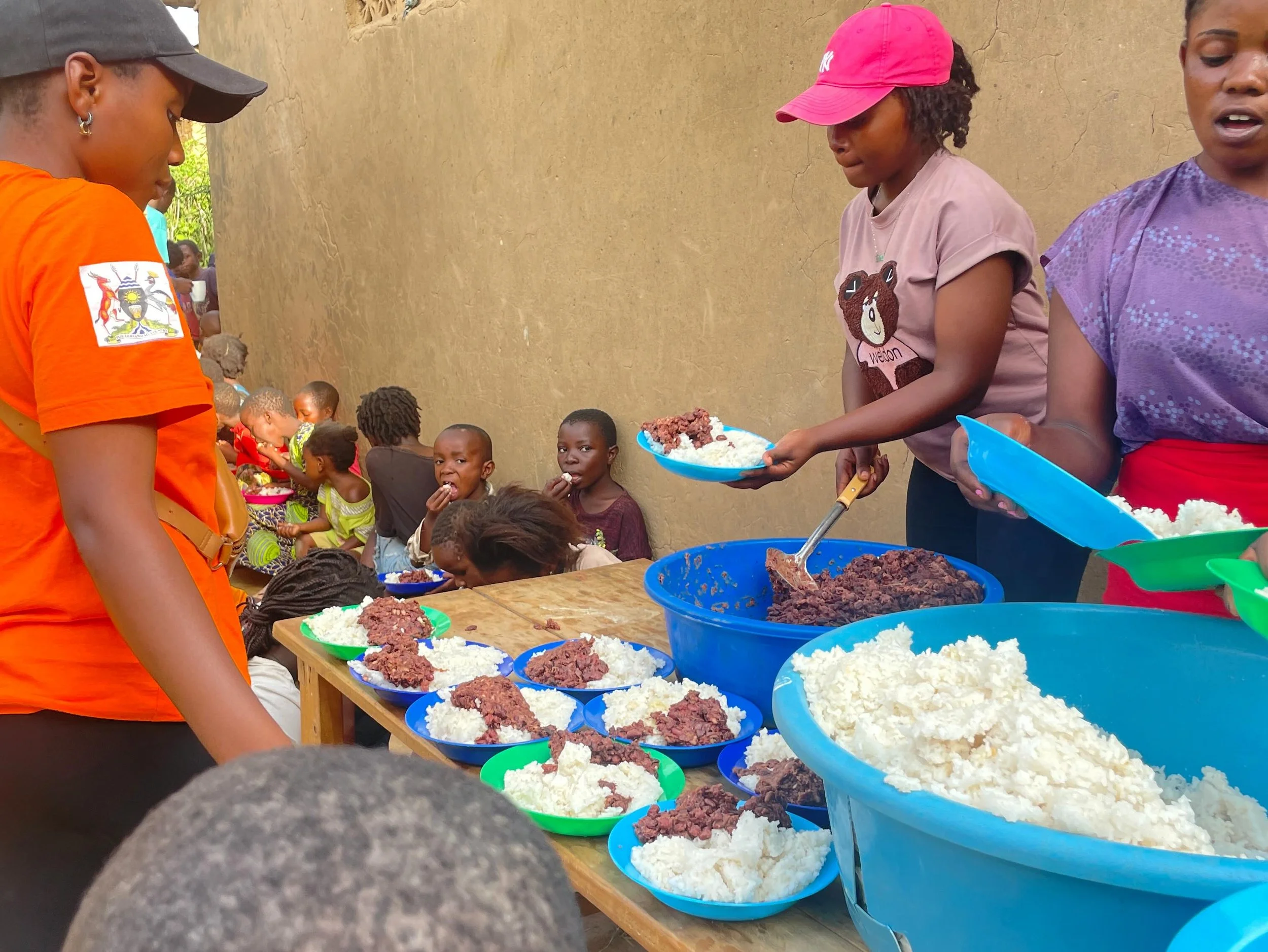 Women serving and children eating food at an outdoor community event