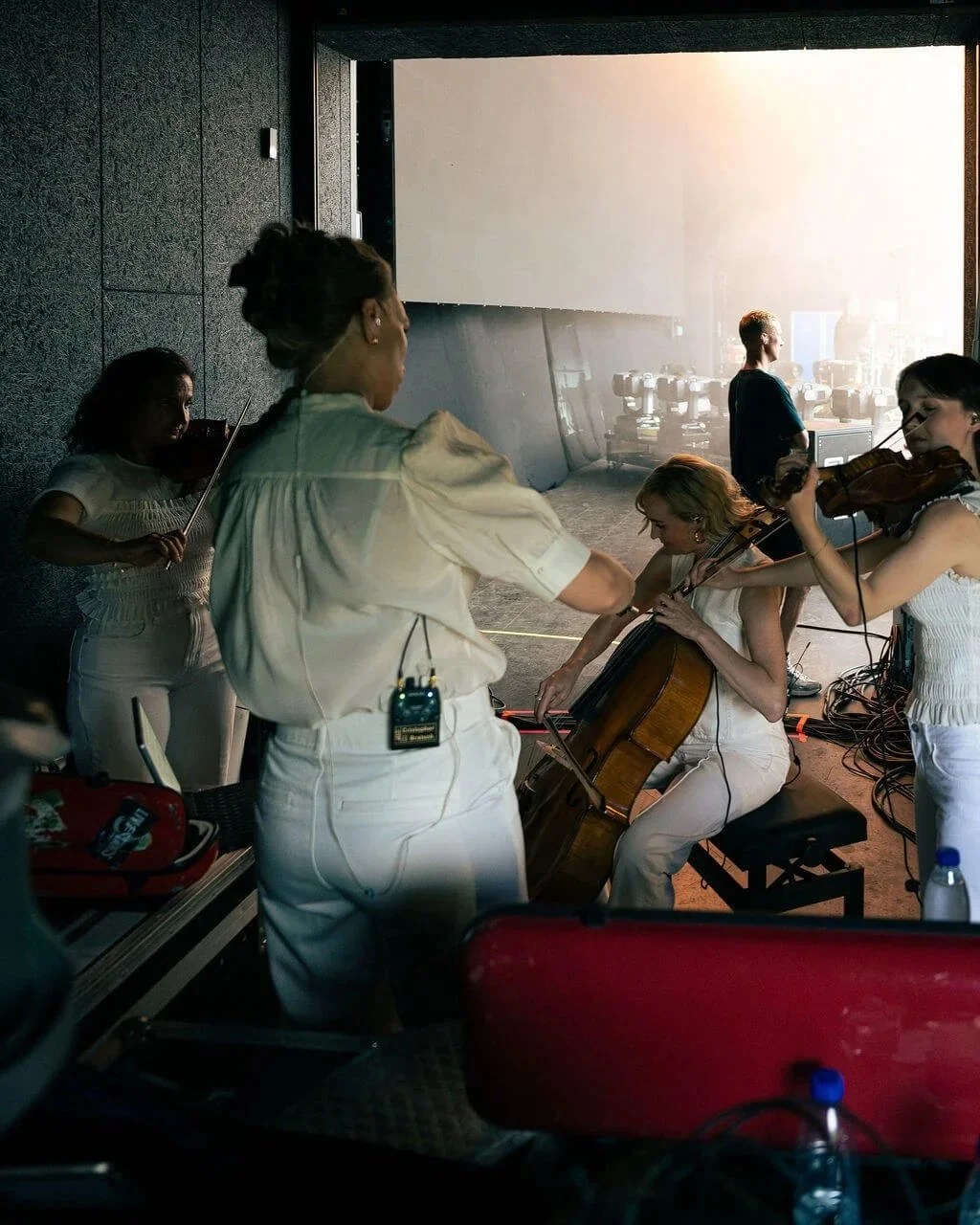 Musicians preparing in a recording studio with sunlight coming through a large window in the background