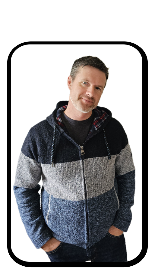 A man with short dark hair and a beard stands against a white background, wearing a multicolored zip-up sweater with a hood, and looks at the camera with a slight smile.
