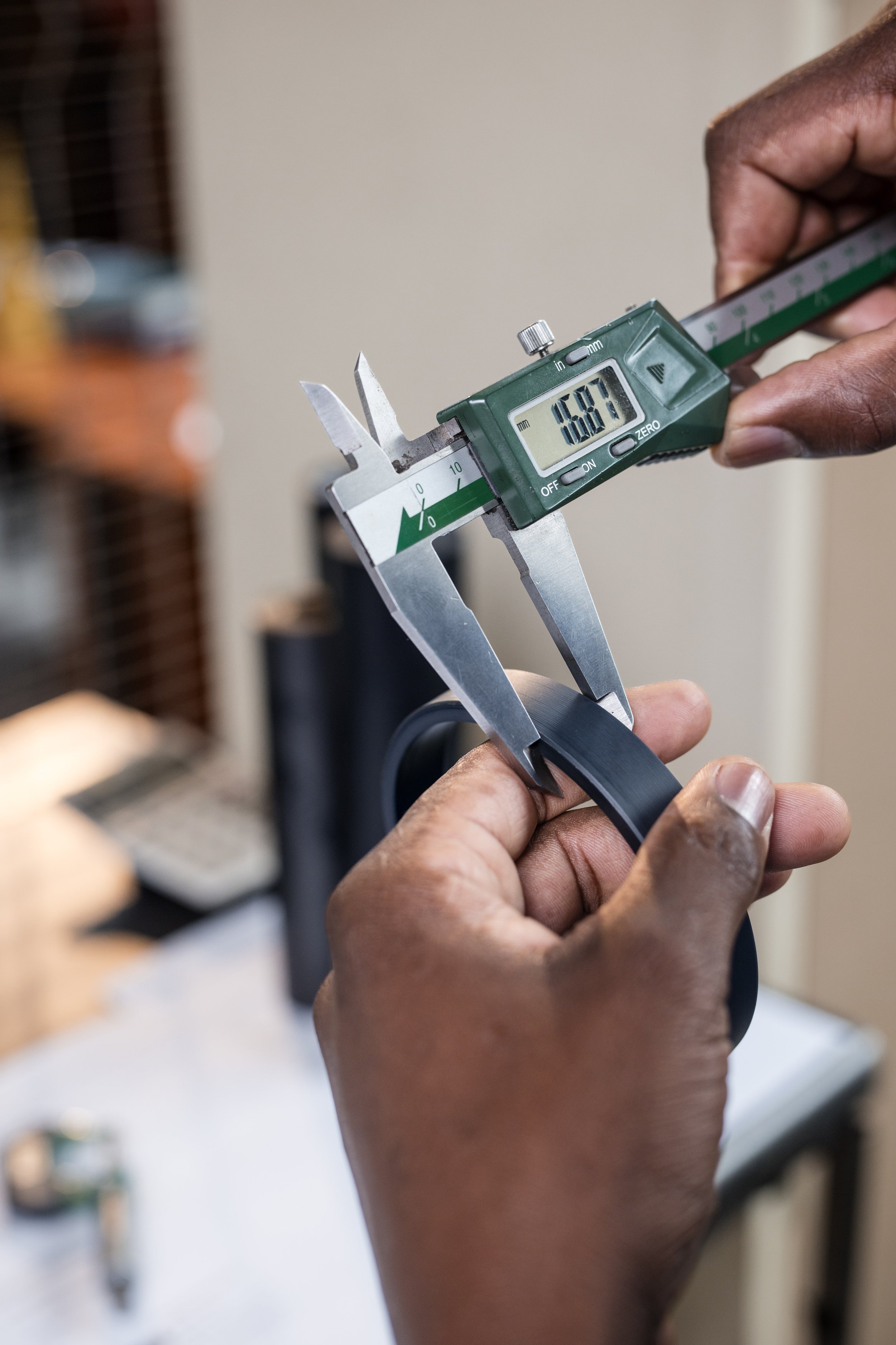 Person measuring a seal with digital caliper in workshop.