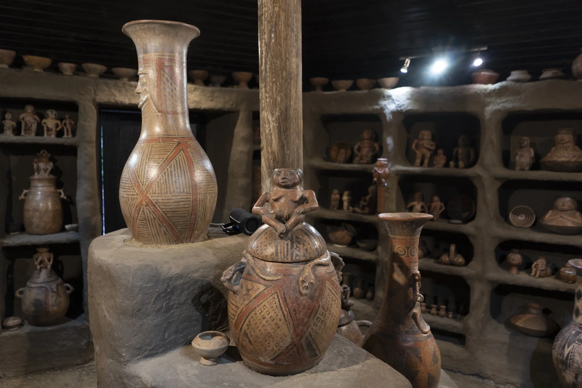Collection of traditional pottery and figurines displayed on shelves and tables inside a museum or cultural exhibit.