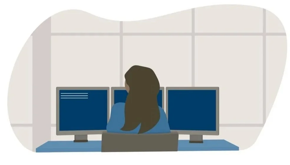 Illustration of a woman sitting at a desk with three computer monitors in an office setting.