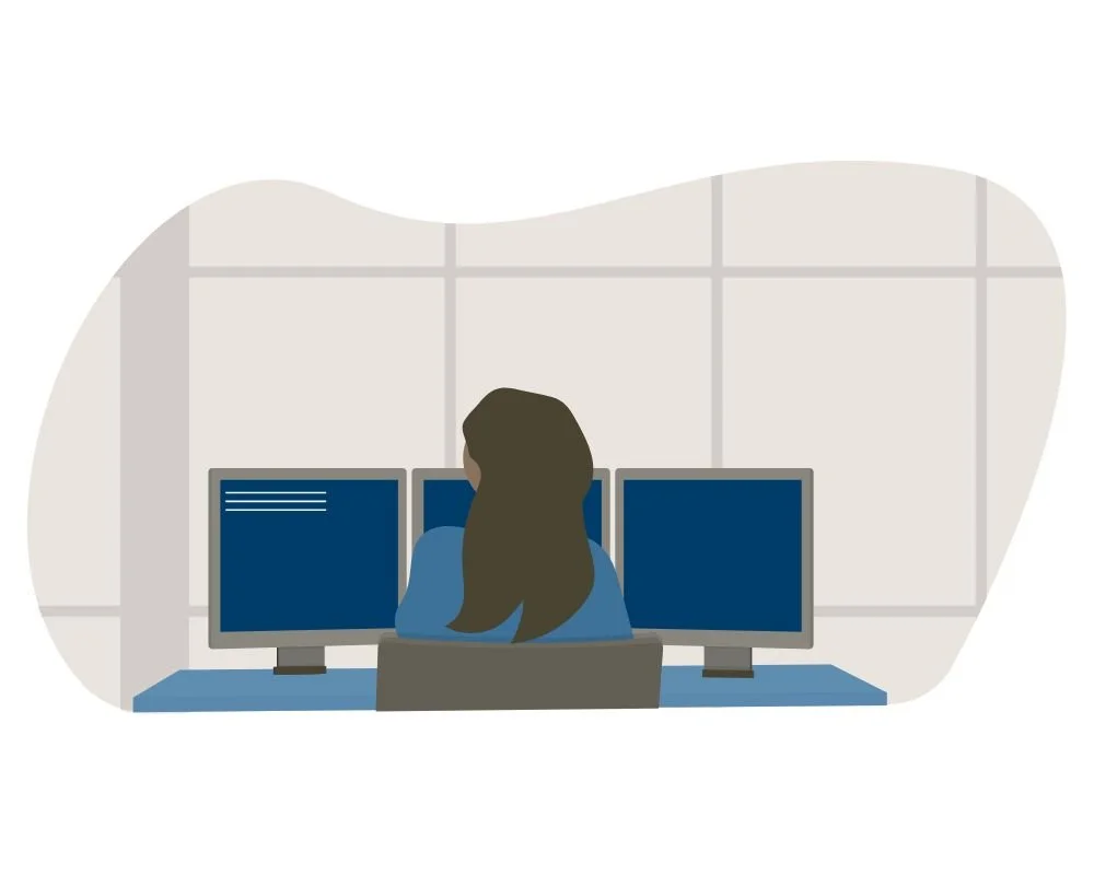 Person working at a desk with three computer monitors in a modern office.