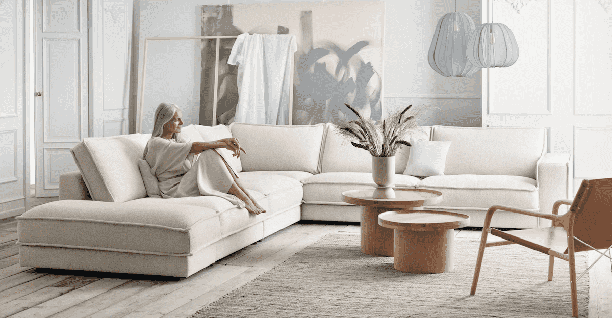 Frau in einem hell gestalteten Wohnzimmer auf einem bequemen Sofa sitzend