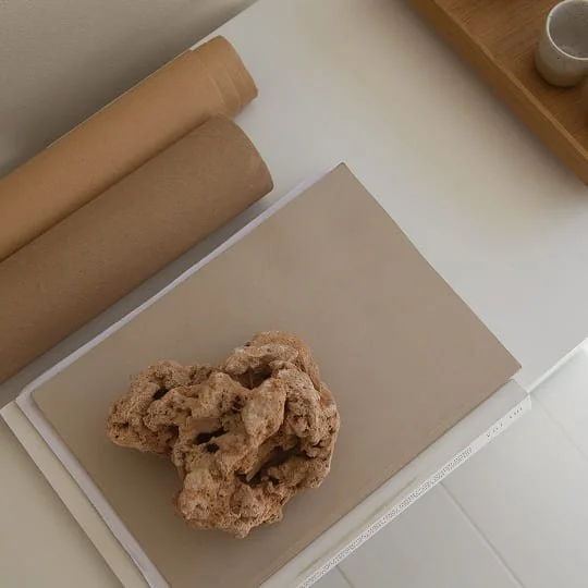 Kunstprojekt mit Ton, Papierrollen und einem Skulpturobjekt auf einem Schreibtisch