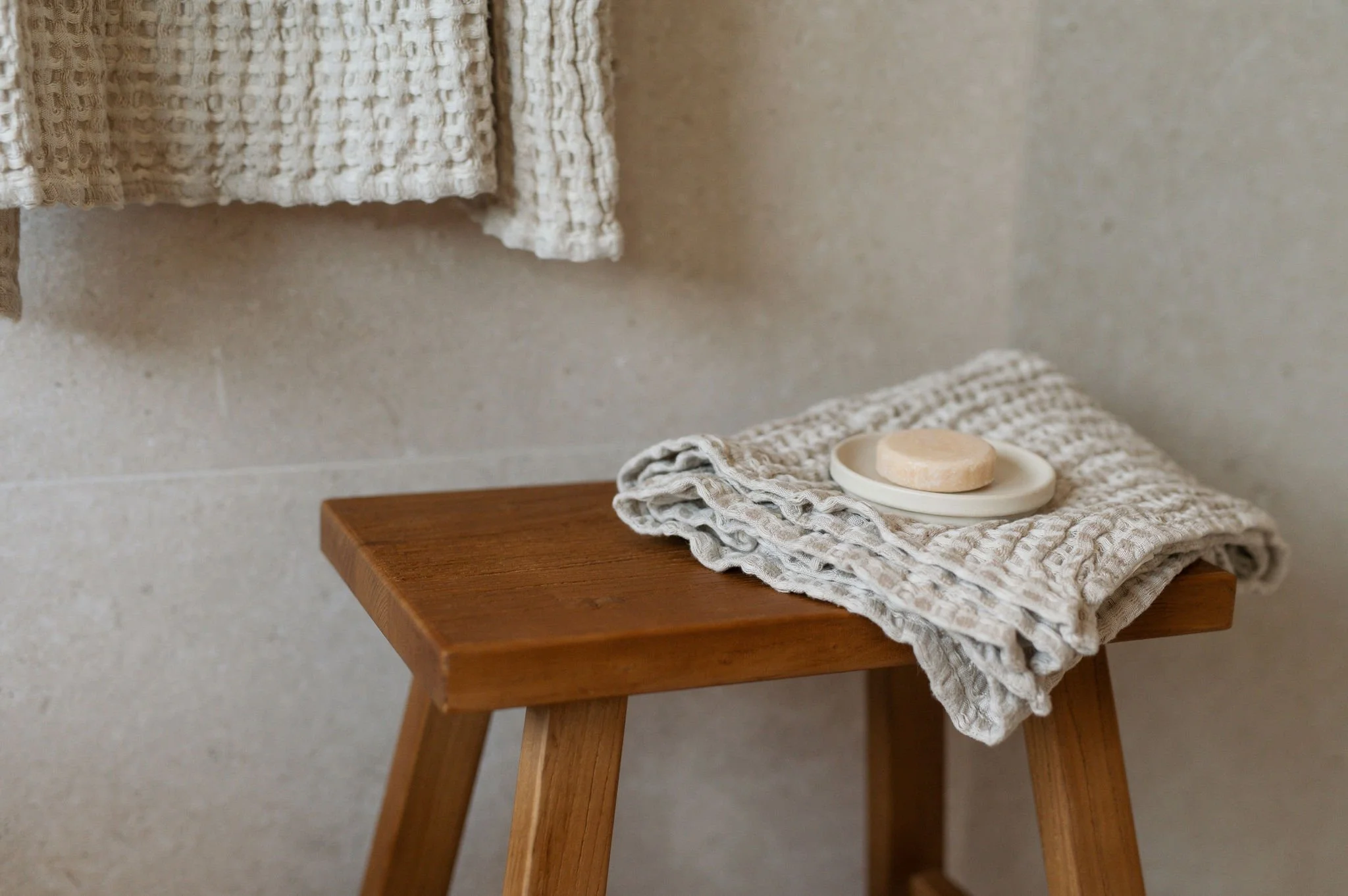 Holzhocker mit grobem Handtuch und Seife in einem Badezimmer