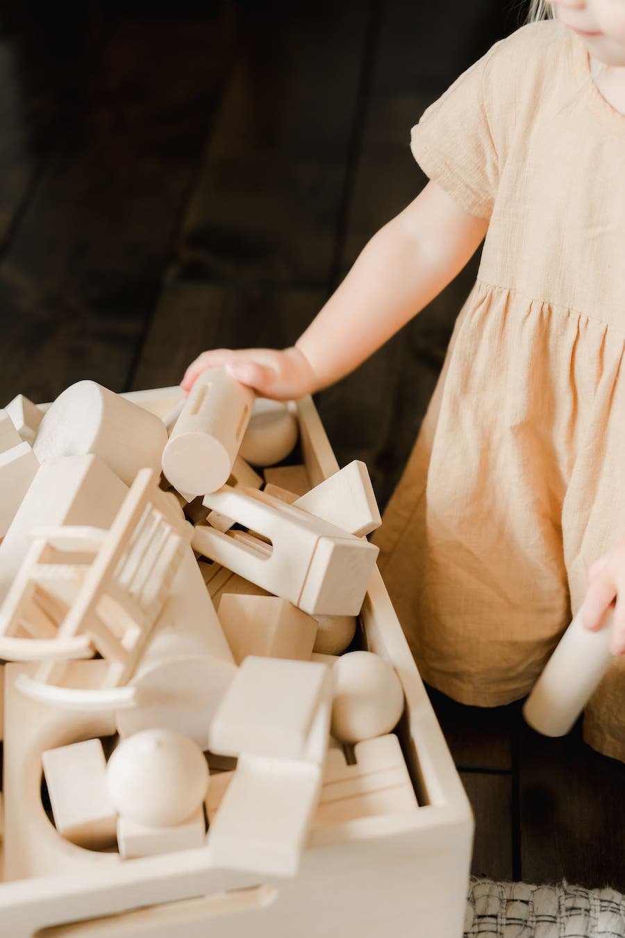 Mädchen legt Spielsachen in eine Holzkiste