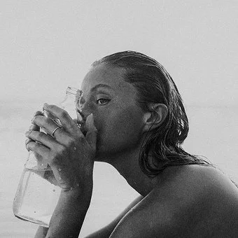 Junge langhaarige  Frau mit einer Karaffe Wasser in der Hand