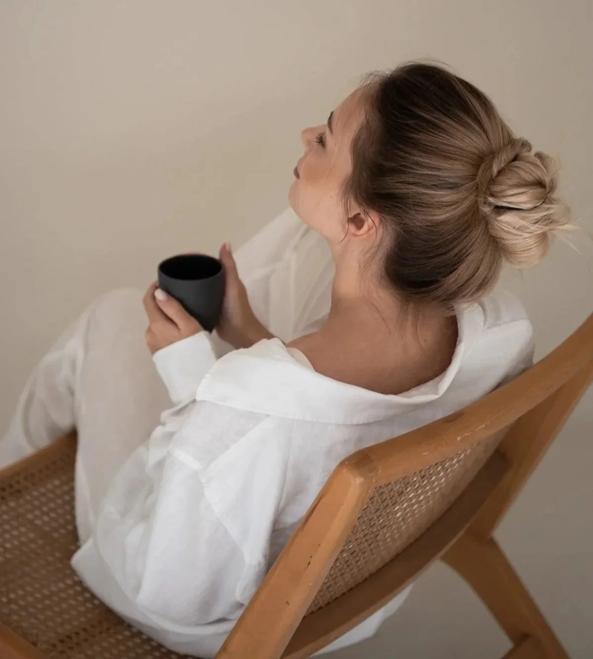 Entspannende Frau auf Flechtsessel mit Kaffeetasse in der Hand