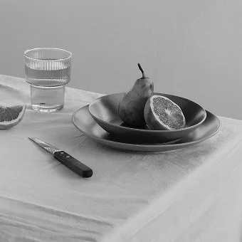 Tisch mit Leinentischdecke und einem Gedeck mit Obstschale