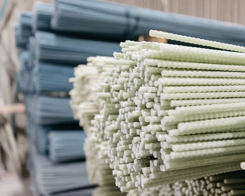 Stacks of white plastic or nylon sticks with textured surfaces, stored in an indoor warehouse.