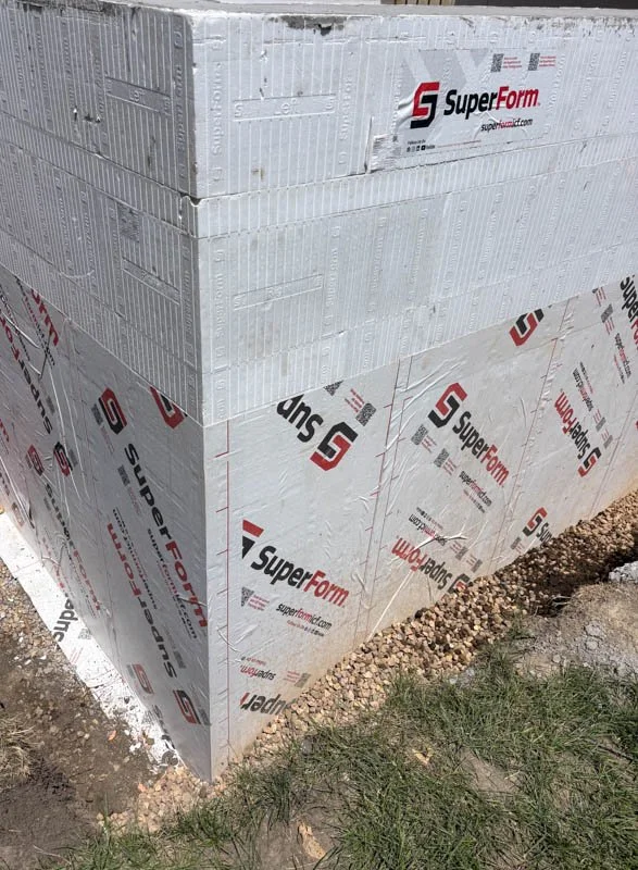 Close-up of a corner of a building under construction with white insulation panels labeled SuperForm.