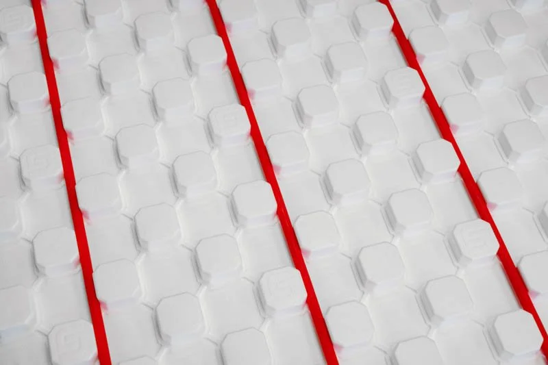 Close-up of a SuperPex Panel with 3 red pipes being held by it