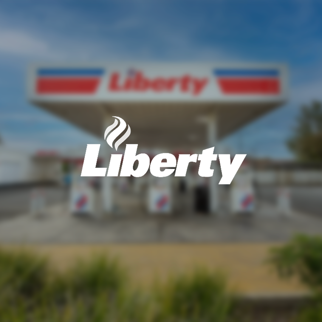 A blurred image of a Liberty gas station with gas pumps in front and a sign that reads 'Liberty' on the building and on the logo.