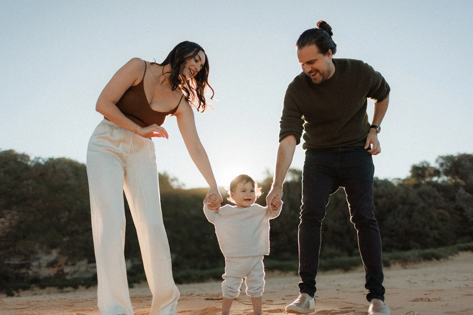 Couple on beach with toddler girl taking her first steps